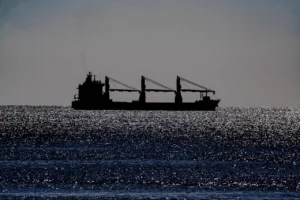 Frachter mit Ladekränen als Silhouette auf glitzernder See: Führung in der Werftzeit